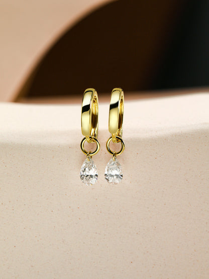 Pear diamond drop huggie earrings in 18K gold on sandstone