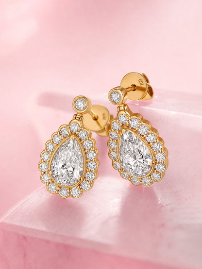 Pear-cut diamond halo drop earrings in 18K gold, angled view showing bezel-set top stone