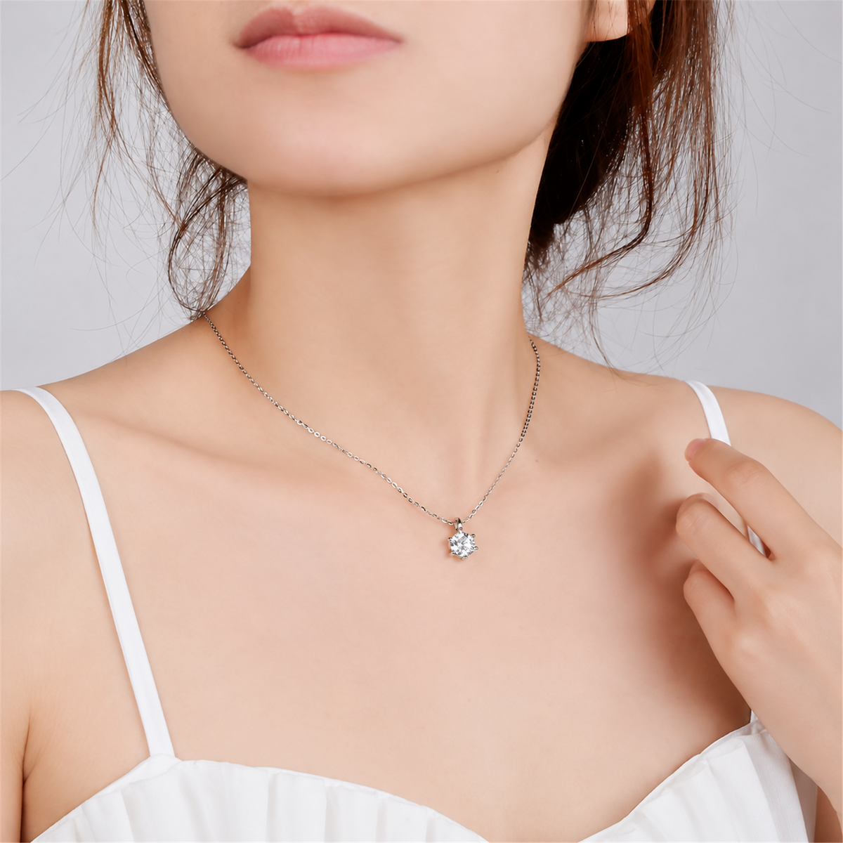 Diamond pendant necklace worn with a white top, square portrait