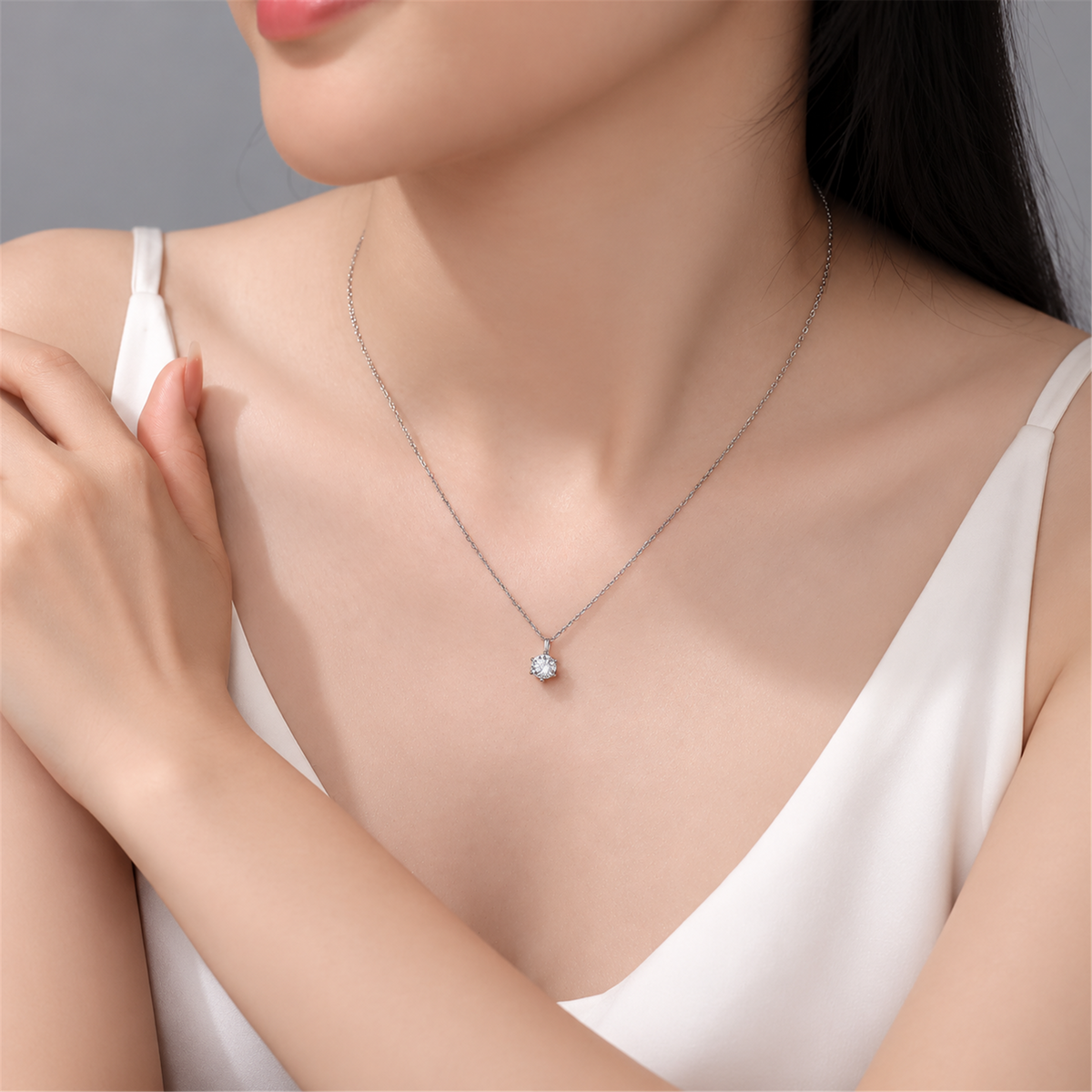 Six-prong diamond pendant necklace worn with white clothing, portrait
