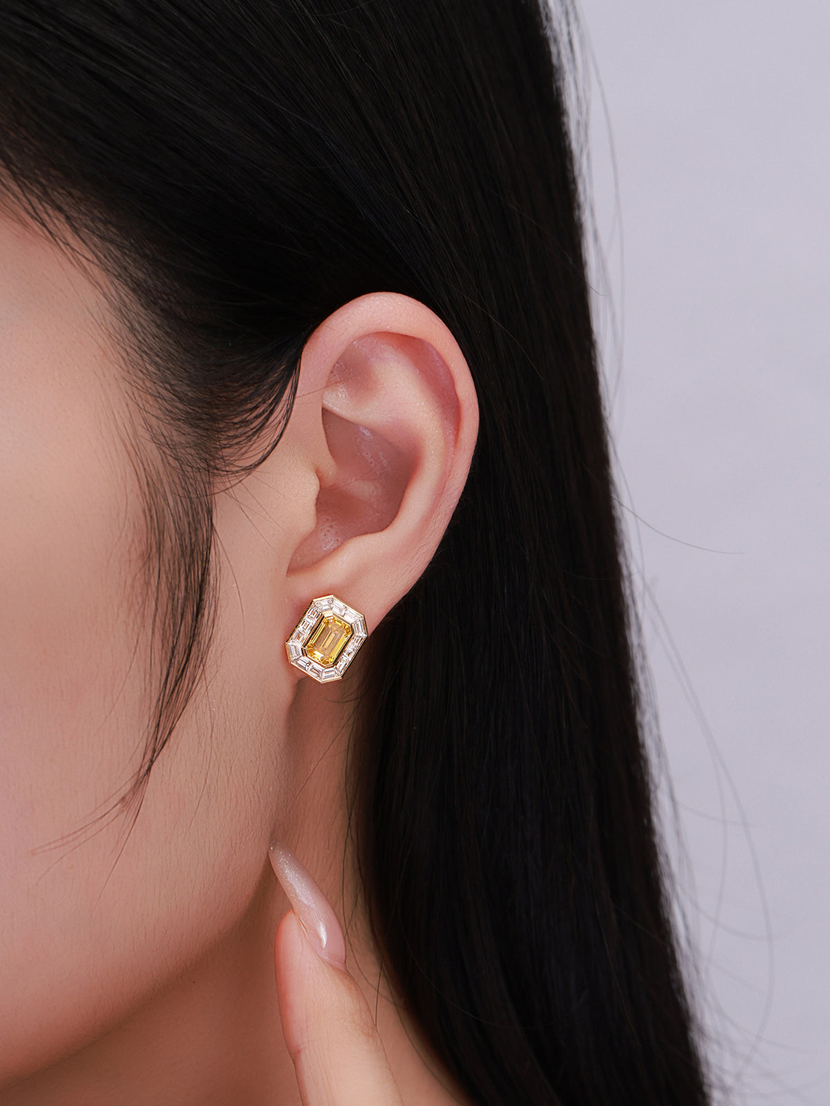 Model wearing emerald-cut yellow lab-grown diamond halo stud earring
