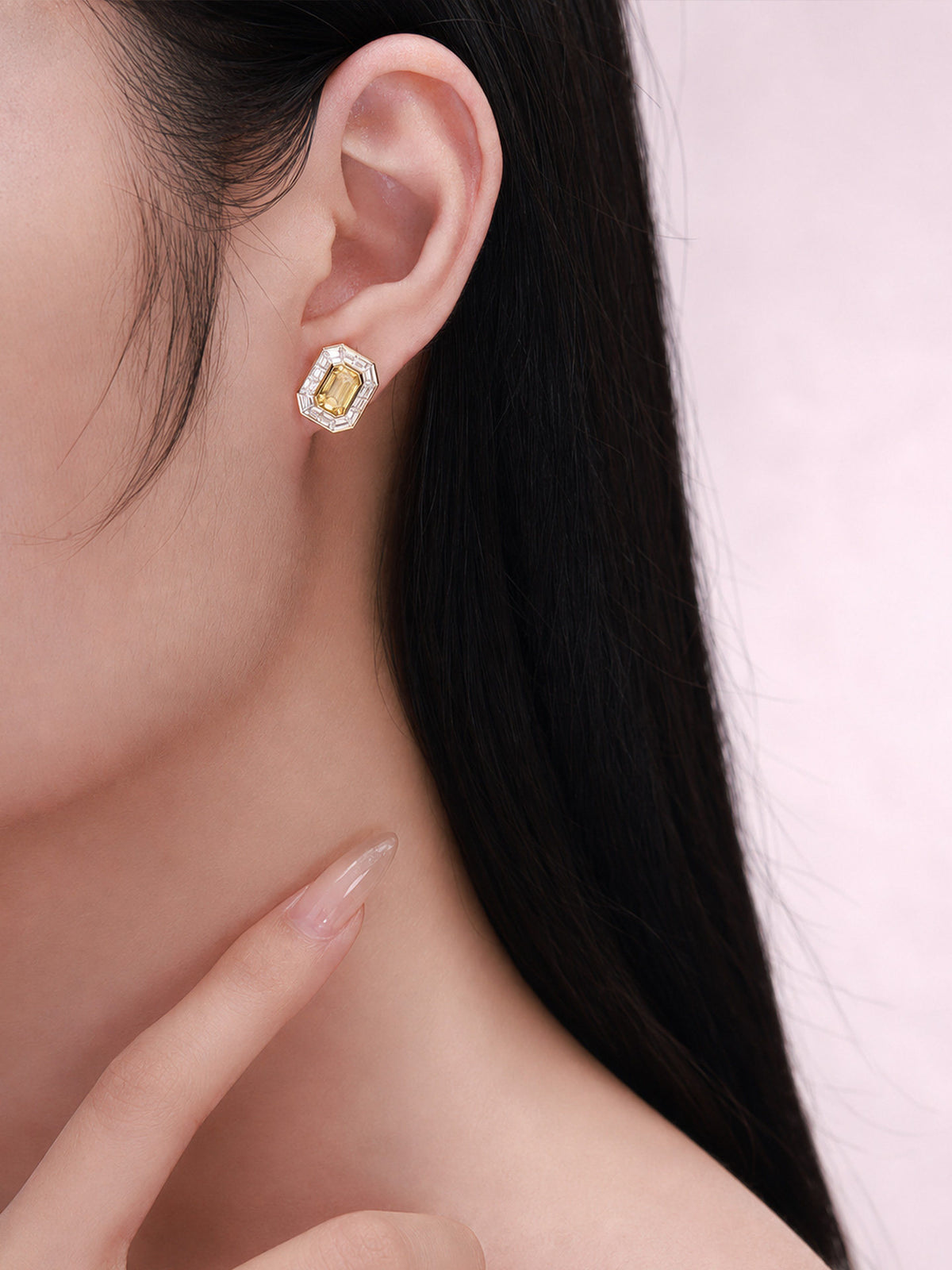 Yellow diamond halo stud earring on the ear, close-up