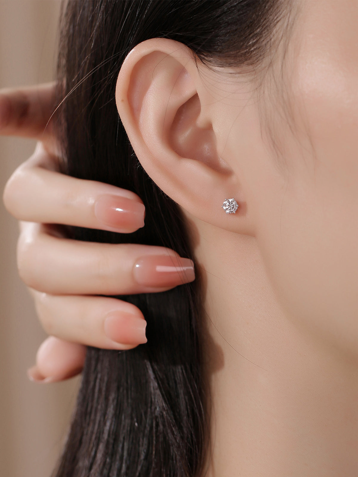 Close-up of a six-prong round diamond stud earring on the ear