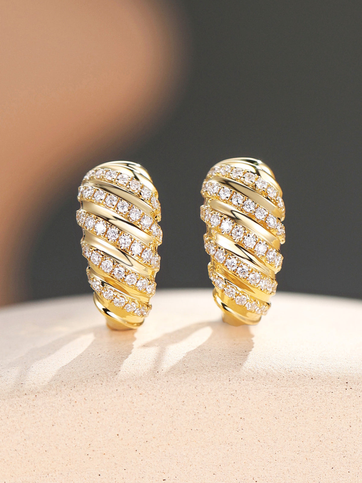 Close-up of Torsade pavé lab-grown diamond rows on 18K yellow gold huggie earrings
