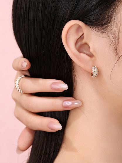 Torsade 18K gold pavé diamond huggie earrings worn close to the ear