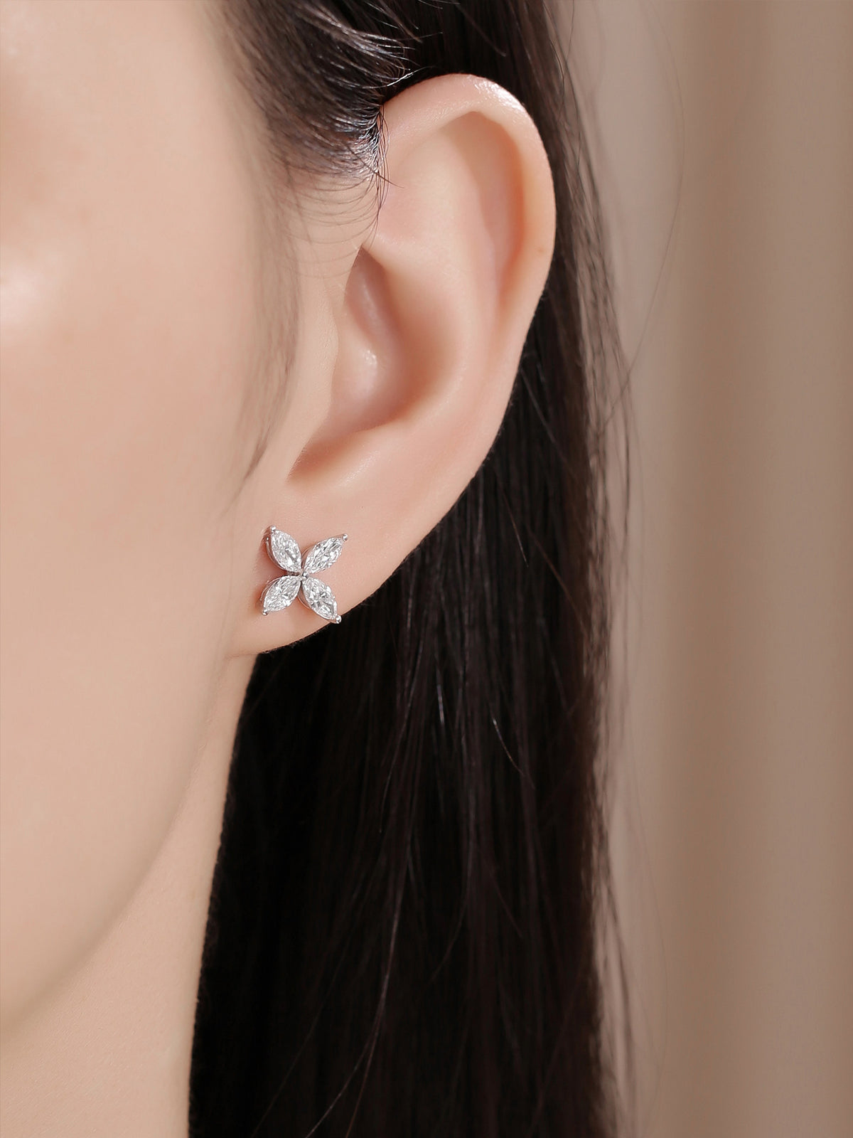 Close-up of the four-petal platinum diamond stud earring worn on the ear