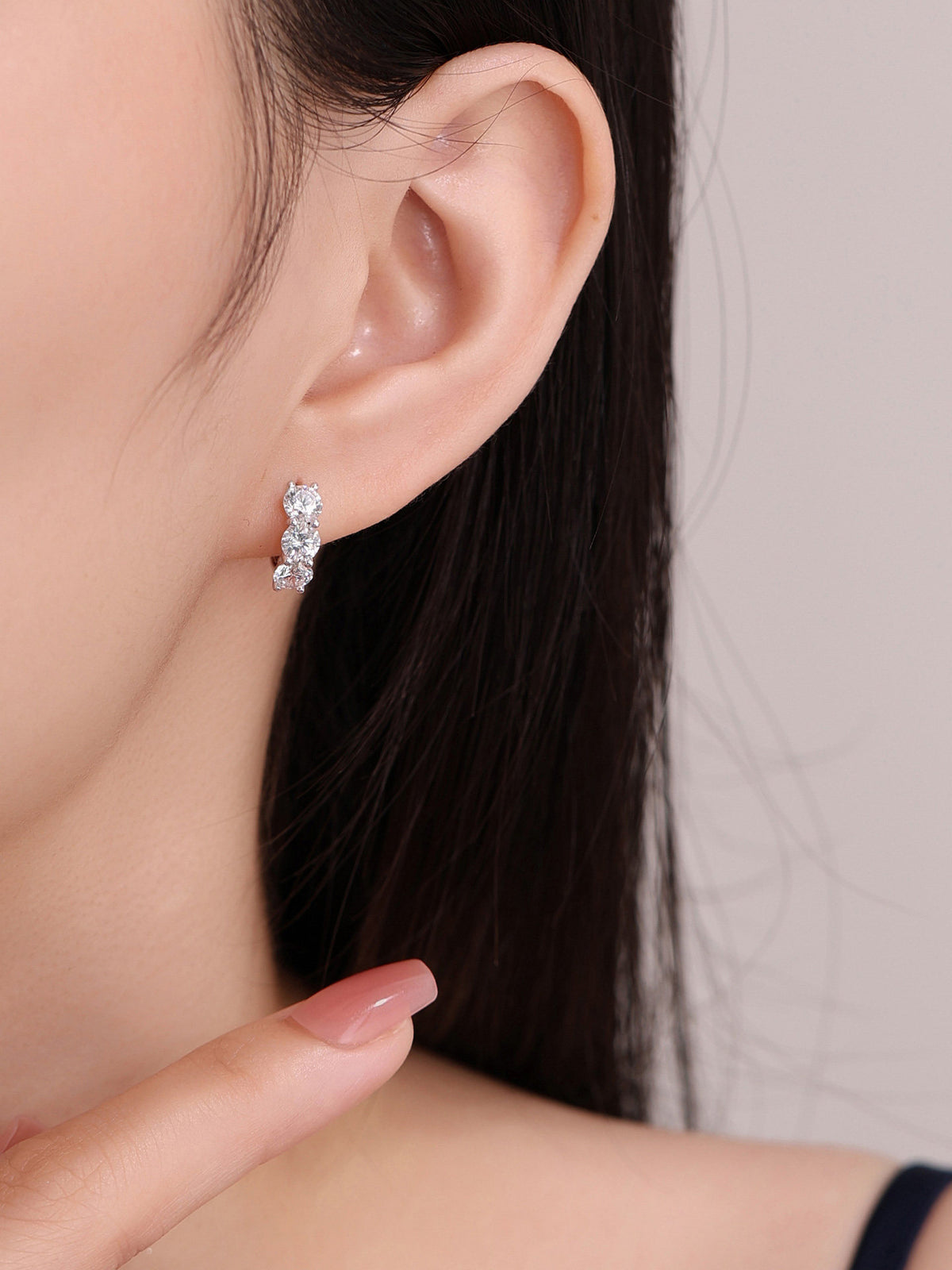 Three-stone diamond huggie earring, side view on model