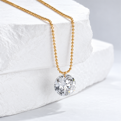 Yellow gold bead chain and round diamond pendant on a white stone display; digitally retouched supplier image