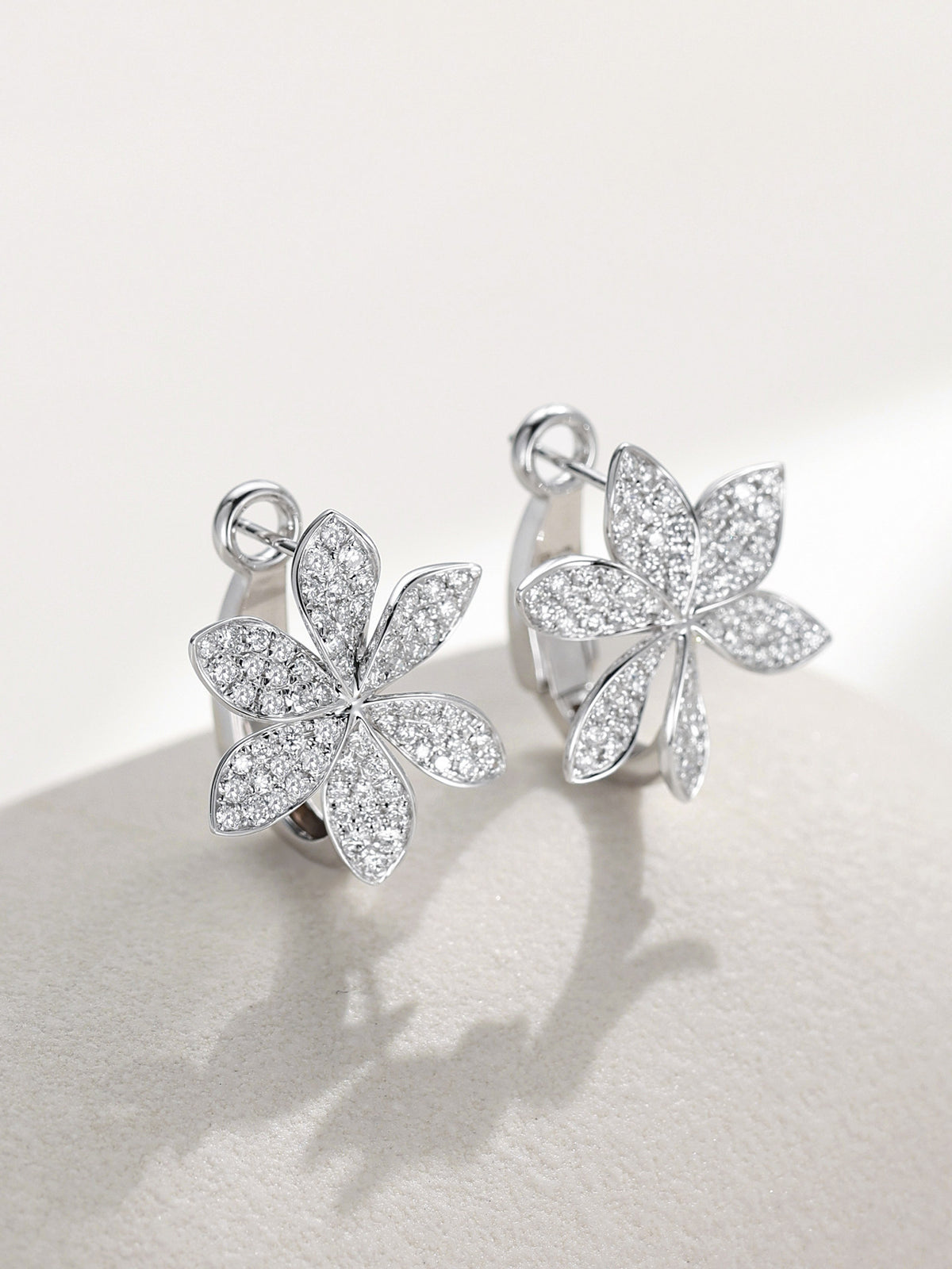 Six-petal pavé diamond flower huggie earrings, angled view
