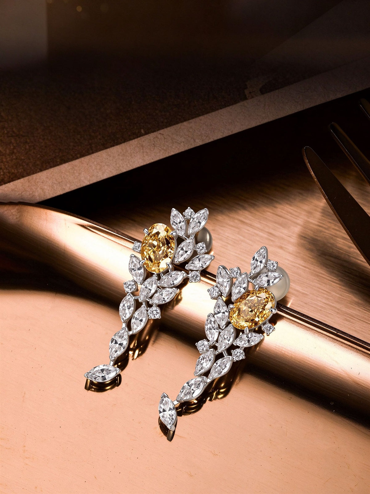 Fancy yellow lab-grown diamond drop earrings with marquise diamonds resting on rose gold surface